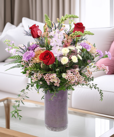 Love's Delight is designed in flirty pinks and purples showcasing snapragons, carnations, fragrant stock, disbuds and charming accents in a lavender cylinder vase.