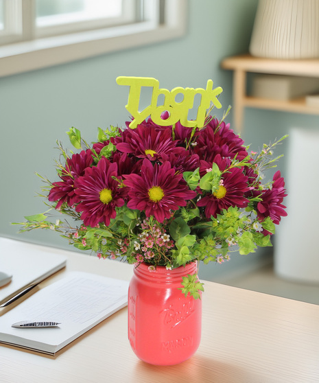 Daisies and accent blooms in a colored mason jar vase with a Thank You pick. A warm and heartfelt gift for Administrative Professionals Week