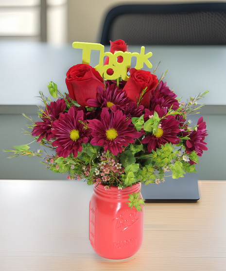 Daisies and accent blooms in a colored mason jar vase with a Thank You pick. A warm and heartfelt gift for Administrative Professionals Week