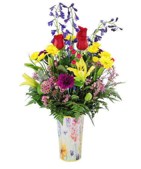 A botanical pail overflowing with a  mix of seasonal blossoms, this arrangement showcases the tall spires of delphinium, Asiatic lilies, carnations and more. 