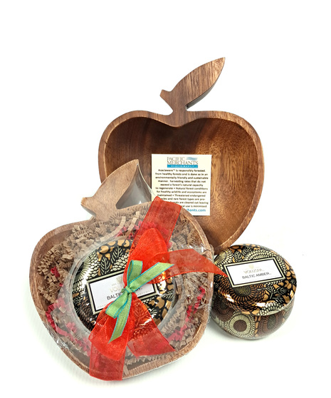 An apple shaped bowl made from acacia wood with a mini tin candle from Voluspa.