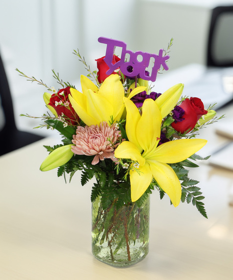 Asiatic lilies, cremons, and pixie carnations in a colored mason jar vase. A fresh and colorful gift for Administrative Professionals Week
