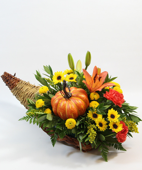 This bountiful design features an orange Asiatic lily, a radiant sunflower, cheerful orange carnations, yellow Viking poms, and a whimsical faux pumpkin