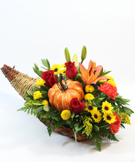 This bountiful design features an orange Asiatic lily, a radiant sunflower, cheerful orange carnations, yellow Viking poms, and a whimsical faux pumpkin