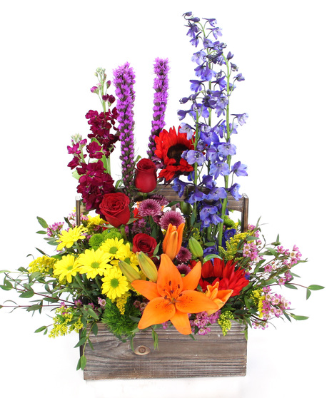 Perfect for those who are drawn to the outdoors, this bouquet is evocative of a wildflower meadow with delphinium, liatris, sunflowers, Asiatic lilies & more in a wooden box.