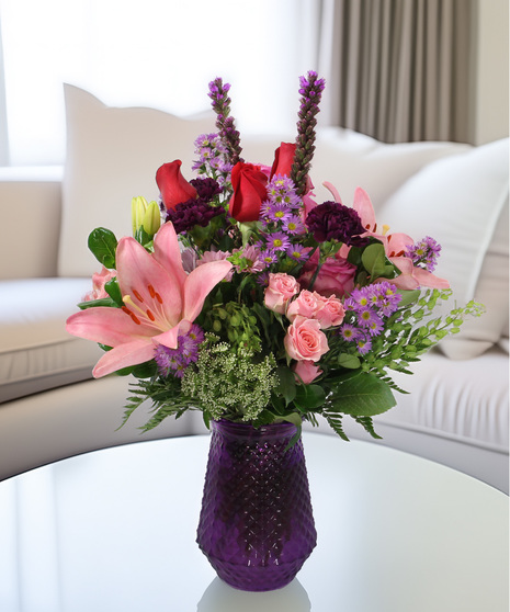 Poetry bouquet with pink lilies, purple carnations & roses in a purple vase. Romantic floral gift in pink and purple tones