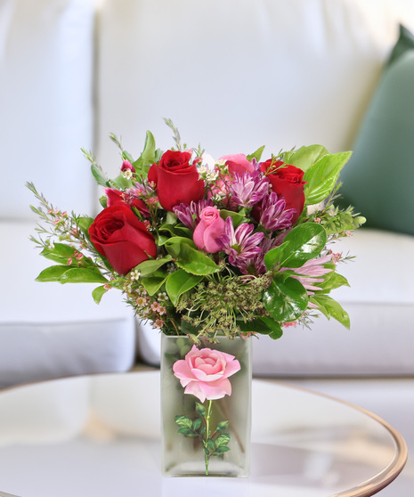 Rose Delight bouquet with pink and purple roses and daisies in a frosted vase with rose design. A beautiful Mother’s Day gift.