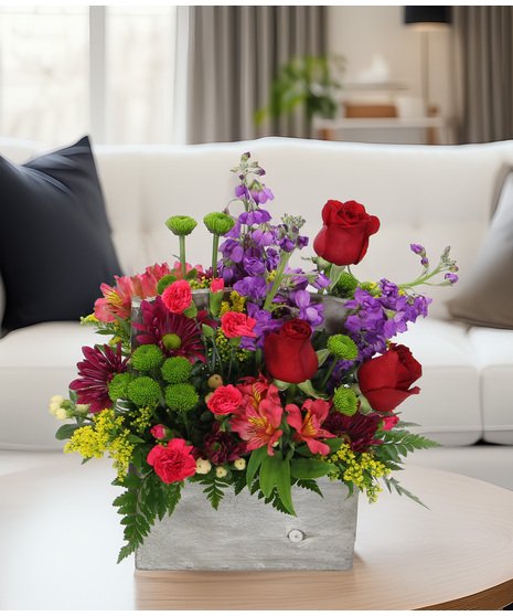 Fragrant stock, Peruvian lilies, daisies, and more in a weathered wooden box. A lush wildflower style spring bouquet bursting with color.
