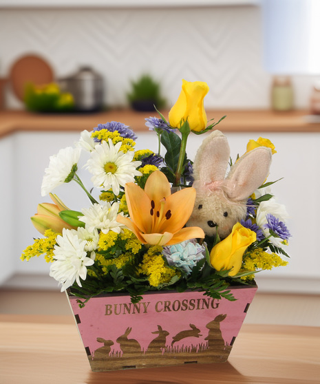 A playful Easter bouquet of lilies, daisies, and rainbow carnations in a bunny silhouette wooden box. A charming gift for the whole family.