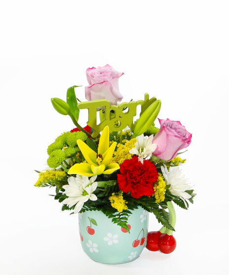 a cheerful bouquet arranged in a ceramic mug with cherries & white daisies with a cherry stem handle featuring yellow Asiatic lilies, red carnations, kermits and white daisies