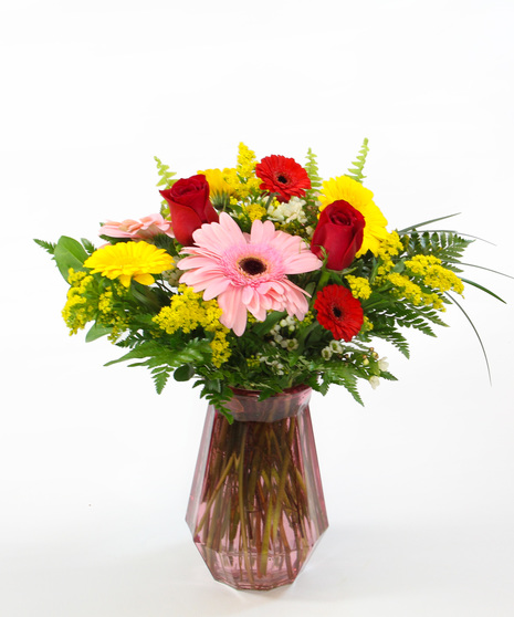 Daisy Fun bouquet with gerbera daisies in three sizes in a footed pink vase. Cheerful and charming floral gift perfect for gifting.