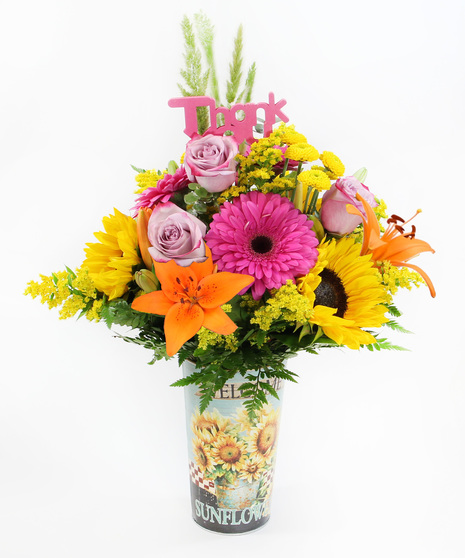 a vibrant bouquet in a charming sunflower tin, featuring cheerful sunflowers, hot pink gerbera daisies, and bright orange Asiatic lilies accented with a festive Thank You pick