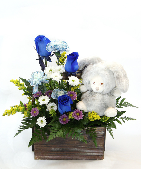 Our New Arrival bouquet is available in pink or blue tones, this design comes nestled in a wooden box, accompanied by a plush bear in a costume. 