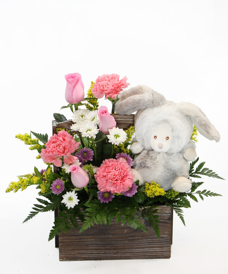 Our New Arrival bouquet is available in pink or blue tones, this design comes nestled in a wooden box, accompanied by a plush bear in a costume. 
