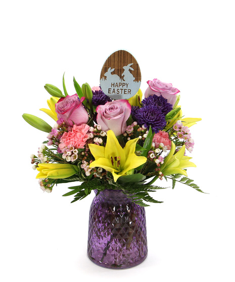 Celebrate Easter with this bright bouquet of Asiatic lilies, carnations and button poms in a colored glass vase with Happy Easter pick.