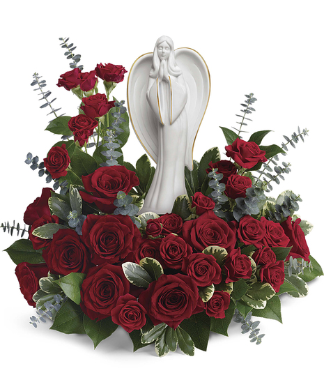 This peaceful porcelain angel sculpture, surrounded by radiant red roses and delicate greenery, is a touching tribute to a rich life.